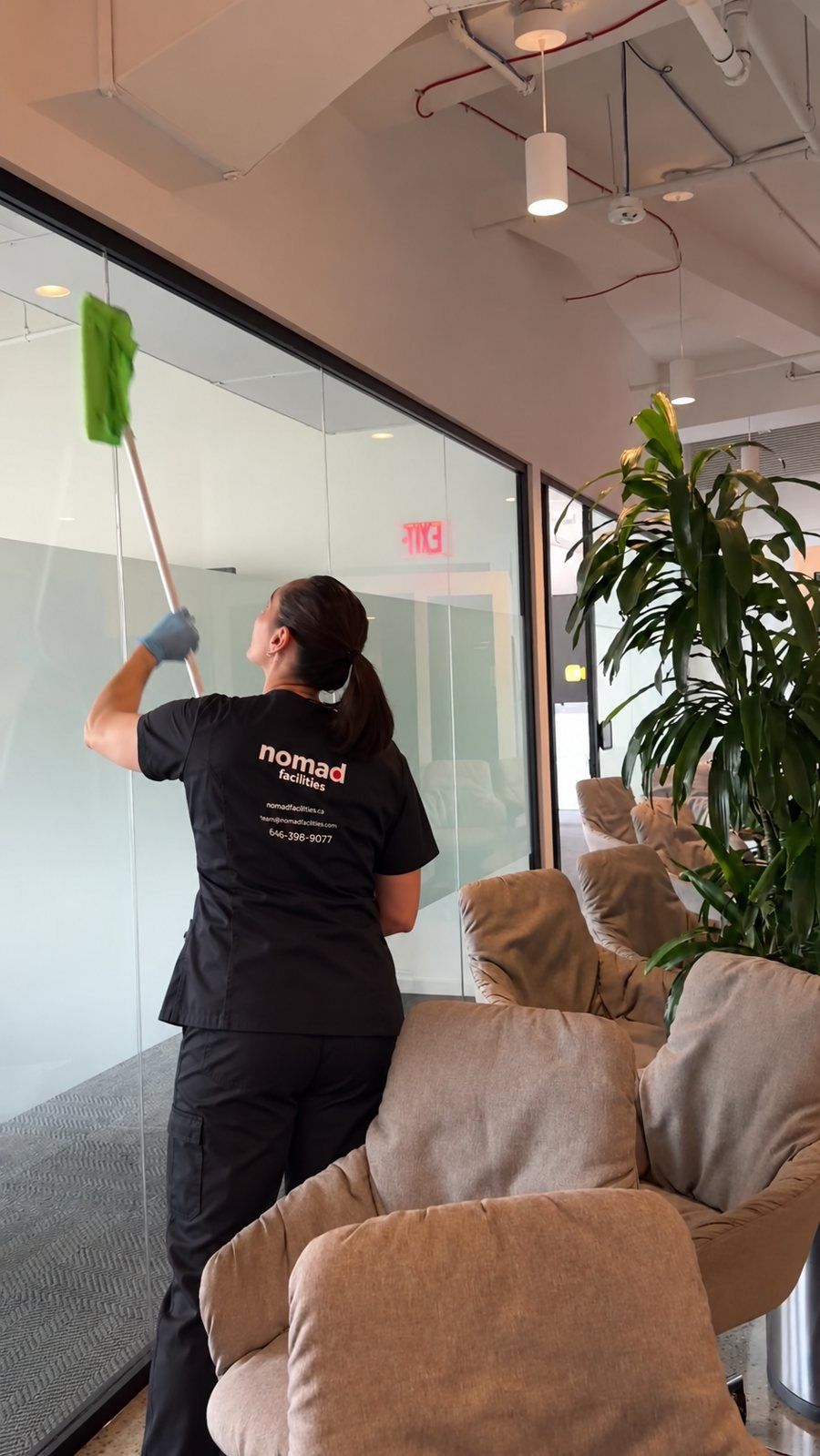 A Nomad Facilities team member cleaning the glass walls of a shared office space